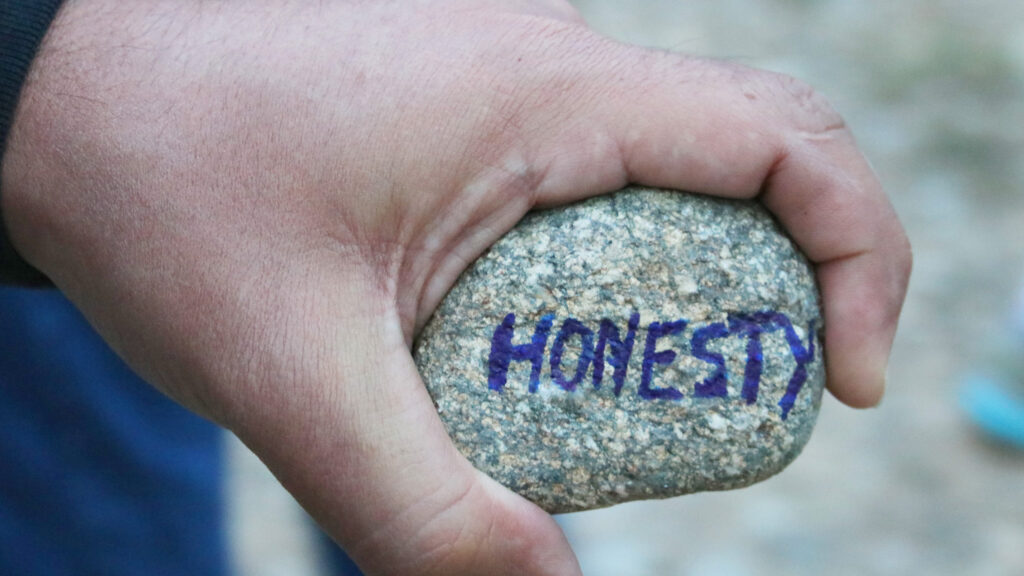 hand holding rock that says "honesty"