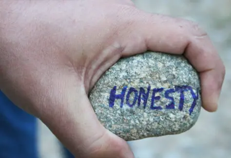hand holding rock that says "honesty"